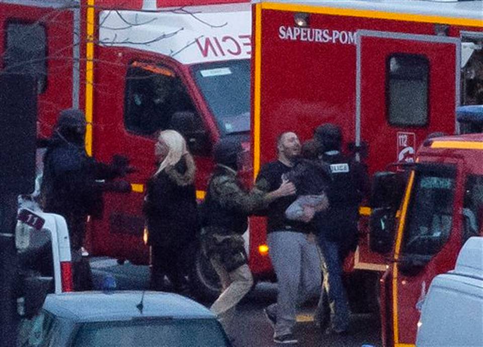 ALTERNATE CROP OF XPDA123 - A security officer directs released hostages after they stormed a kosher market to end a hostage situation, Paris, Friday, Jan. 9, 2015. Explosions and gunshots were heard as police forces stormed a kosher grocery in Paris where a gunman was holding at least five people hostage. MICHEL EULER AP PHOTO