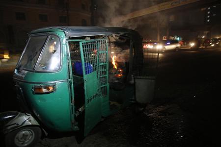 An auto rickshaw burns after being set on fire along a street in Dhaka