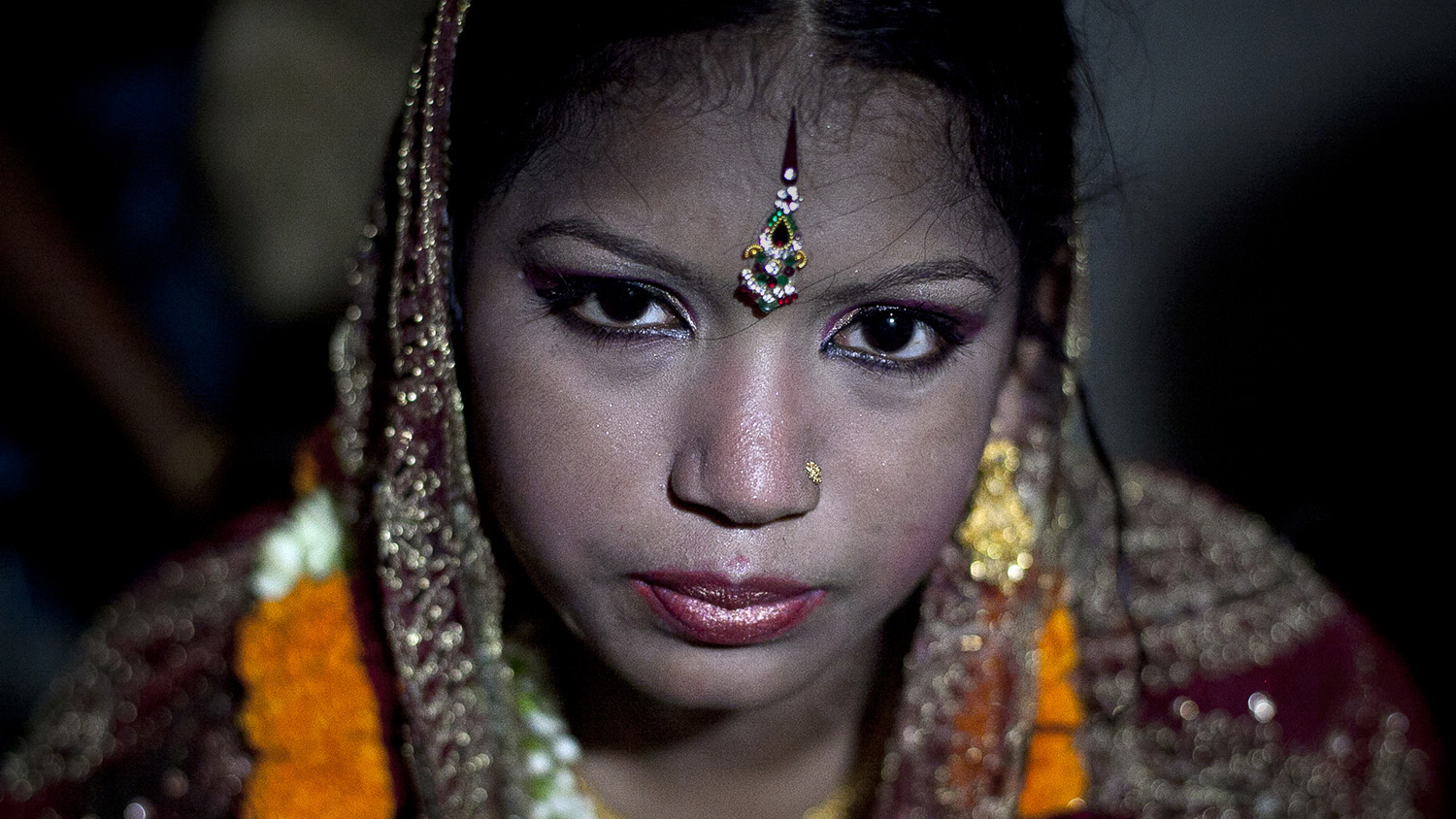 13 year old Runa Akhter is seen the day of her wedding to a 29 year old man August 29, 2014 in Manikganj, Bangladesh. Runa was in the 7th grade, and loved reading, sports and traveling. She wanted to wait until she was 21 to get married but, "No boy want's to marry a girl older than 18 in my village" she said. In June of this year, Human Rights Watch released a damning report about child marriage in Bangladesh. The country has one of the highest rates of child marriage in the world, with 29% of girls marrying before the age of 15, and 65% of girls marrying before they turn 18. The detrimental effects of early marriage on a girl cannot be overstated. Most young brides drop out of school. Pregnant girls from 15-20 are twice as likely to die in childbirth than those 20 or older, while girls under 15 are at five times the risk. Research cites spousal age difference as a significant risk factor for violence and sexual abuse. Child marriage is attributed to both cultural tradition and poverty. Parents believe that it "protects" girls from sexual assault and harassment. Larger  dowries are not required for young girls, and economically, women's earnings are insignificant as compared to men's.