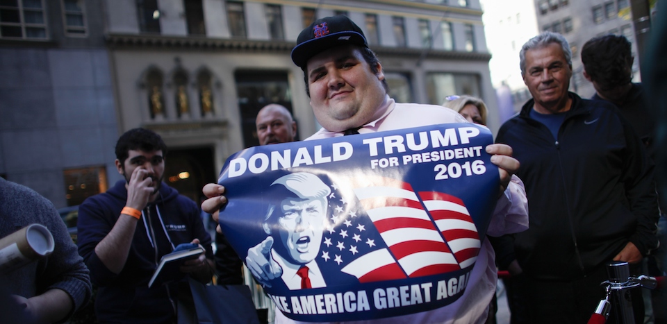 A supporter of Republican presidential hopeful Donald Trump waits in line the launch event for Trump's new book "Crippled America: How to Make America Great Again" outside the Trump Tower on November 3, 2015 in New York. Donald Trump published a book about the ills of America to another media frenzy Tuesday, signing copies for fans, insulting his rivals on the campaign trail and telling Americans to elect him president. "Crippled America: How to Make America Great Again," offers the everyday reader his take on the problems facing the country and why they should elect him to the White House to fix them. AFP PHOTO/Kena Betancur (Photo credit should read KENA BETANCUR/AFP/Getty Images)