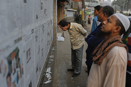 This Saturday, Feb. 20, 2016 photo shows Bangladeshi people reading newspaper early morning in Dhaka, Bangladesh. An editor of one of Bangladesh’s most respected newspapers has sparked an uproar by admitting that eight years ago, he published unsubstantiated reports alleging corruption by Prime Minister Sheikh Hasina, then in the opposition. He says the military fed him the information and pressured him to print it, but it’s the journalist who is feeling the heat more than the country’s long-powerful armed forces. (AP Photo/A. M. Ahad)